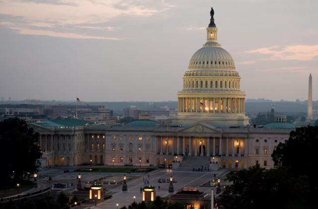 The US Capitol building illuminated against the darkening sky.