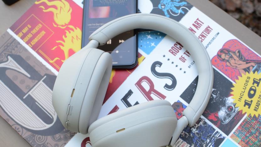 Photo of the Sony WH-1000XM5 headphones in silver sitting on a pile of colorful books.