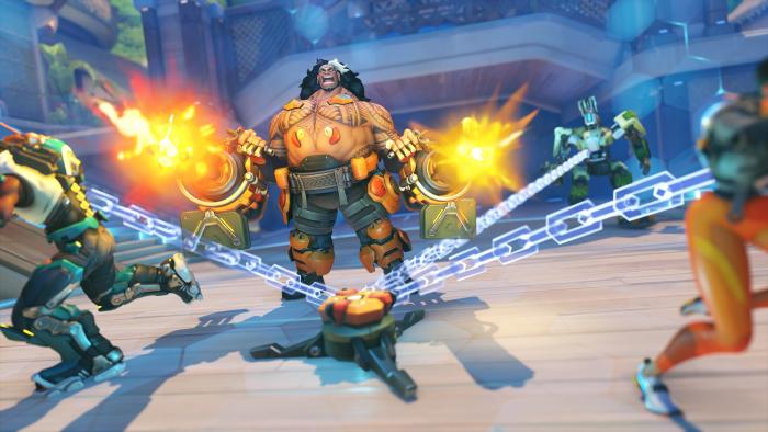 Overwatch 2 hero Mauga fires chainguns as other characters are trapped by transparent chains.