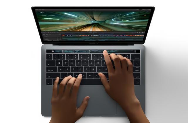 Apple marketing photo of a MacBook Pro with Touch Bar. A person's hands are on the keyboard and Touch Bar.