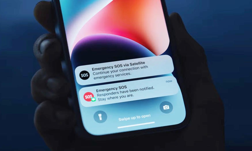 A hand holds up an iphone in a dark show and shows the Apple's Emergency SOS feature on the screen. "Responders have been notified. Stay where you are."