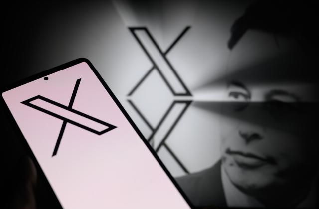 The X logo is being displayed on a smartphone, with the X app, formerly known as Twitter, and X visible in the background, in this photo illustration taken in Brussels, Belgium, on January 5, 2024. (Photo by Jonathan Raa/NurPhoto via Getty Images)