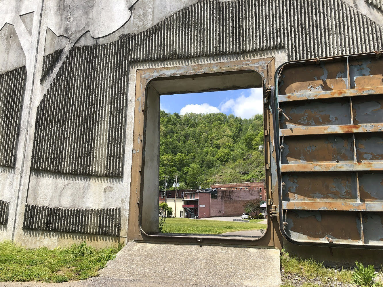 In this Tuesday, May 12, 2020, photo the town of Matewan, W.Va, is shown through a river floodwall gate. A gunfight between miners and detectives hired by a coal company on a Matewan street left 10 people dead on May 19, 1920. It became known as the Matewan Massacre. (AP Photo/John Raby)