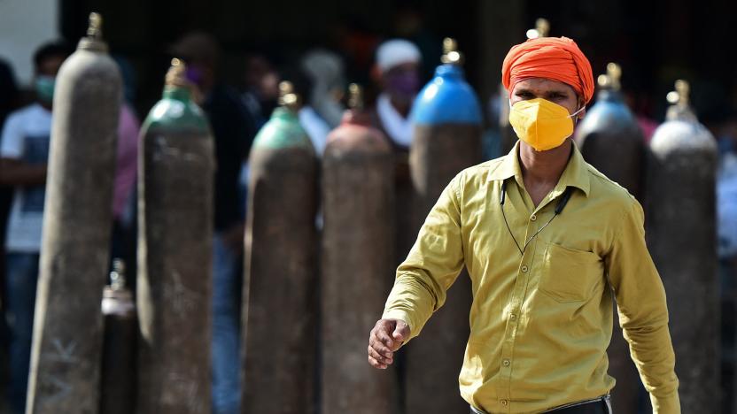 A man walks past people waiting to refill their medical oxygen cylinders for Covid-19 coronavirus patients at an oxygen refilling station in Allahabad on April 24, 2021. (Photo by Sanjay KANOJIA / AFP) (Photo by SANJAY KANOJIA/AFP via Getty Images)