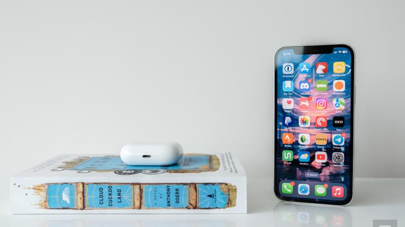 An iPhone 12 next a blue and white book and a pair of AirPods Pro. 