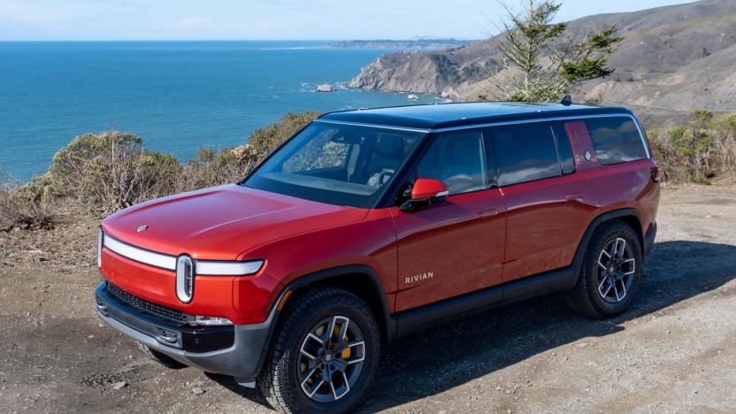 Photo of the Rivian R1S electric SUV (red) sitting by a beach with rocky shores.