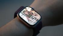 The Apple Watch Series 10 with a Photos watch face open on its home screen, worn on a wrist held in mid-air.