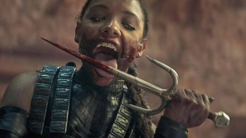 A still from the Mortal Kombat movie, with a human creature licking a bloody weapon.