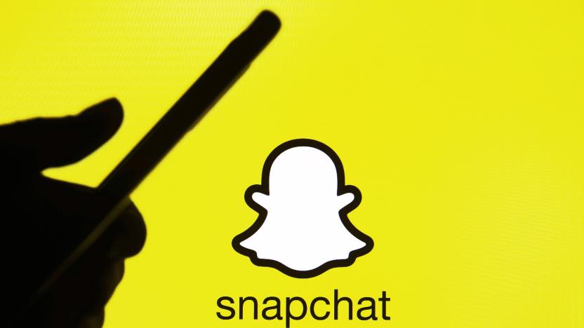 This illustration picture taken on 15 January 2021 shows the Snapchat logo in front of the silhouette of a hand holding a smartphone (Photo illustration by STR/NurPhoto via Getty Images)