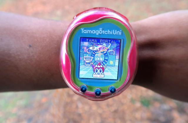 A Tamagotchi Uni worn on the wrist showing the new Tama Portal