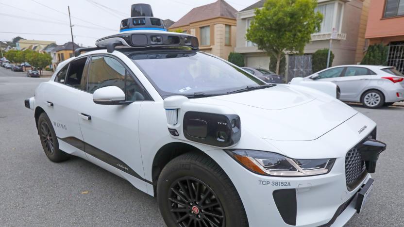 A white Waymo self-driving SUV is parked in the street.