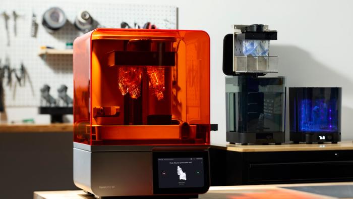 Image of the new Formlabs Form 4 3D printer on a workbench, with other Formlabs' accessories in the background and a pinboard with tools in the blur.