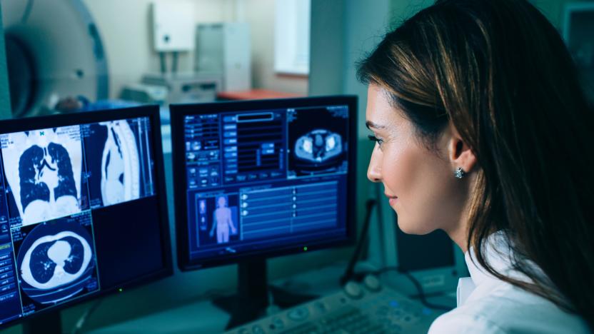 Radiologist reading a CT scan. Female doctor running CT scan from control room at hospital