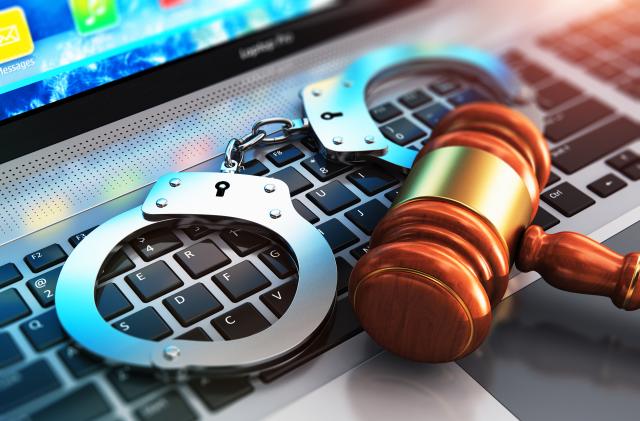 Creative abstract cyber crime, online piracy and internet web hacking concept: 3D render illustration of the macro view of metal handcuffs and wooden judge mallet, gavel or hammer on laptop notebook computer keyboard with selective focus effect