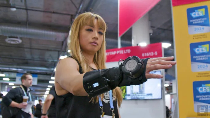 A woman wearing the GyroGlove at the CES 2024, holding her hand out. 