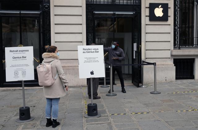 PARIS, FRANCE - OCTOBER 30: A woman wearing a protective face mask queues in front of an Apple store that remained open on the first day of the second national lockdown as part of the COVID-19 measures to fight a second wave of the coronavirus disease (COVID-19) on October 30, 2020 in Paris, France. France has imposed another national lockdown for a minimum of four weeks as the number of coronavirus cases soars during the second wave. Businesses which were defined in the spring as non-essential, including bars, restaurants, museums will be closed. (Photo by Chesnot/Getty Images)