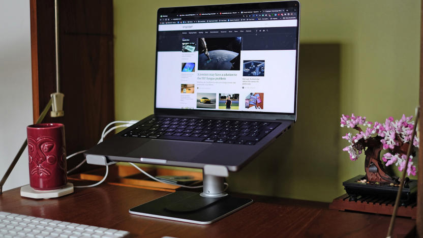 Twelve South’s HiRise Pro laptop stand seen with a laptop on it in a normal desktop setup with keyboard, touchpad and a tiki-style mug.