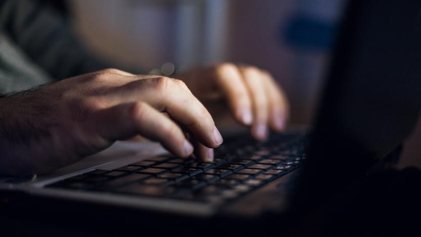 Close up of Unrecognizable man sitting at desk and working on laptop at night