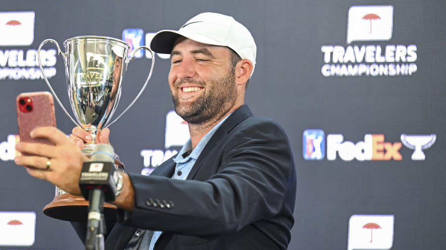 Getty Images - CROMWELL, CONNECTICUT - JUNE 23:  Scottie Scheffler smiles as he takes a selfie with the trophy following his  playoff victory in the final round of the Travelers Championship at TPC River Highlands on June 23, 2024, in Cromwell, Connecticut. (Photo by Keyur Khamar/PGA TOUR via Getty Images)