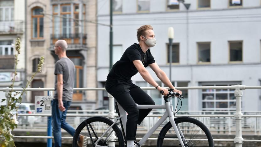 A Cowboy's employee, wearing a protective face mask, rides a Cowboy electric bike in the streets of Brussels, on July 28, 2020. - What better partner for a Cowboy than a Prancing Horse?
The Agnelli family's Exor holding company is best known as the owner of Ferrari, the four-wheeled super car with the stallion logo.
Now, it has joined the race to invest in e-bikes with Belgian e-bike start-up Cowboy, as the two-wheeled electric commuter market shifts up a gear. (Photo by JOHN THYS / AFP) (Photo by JOHN THYS/AFP via Getty Images)