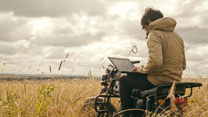 Mari man using laptop on motorcycle in rural field