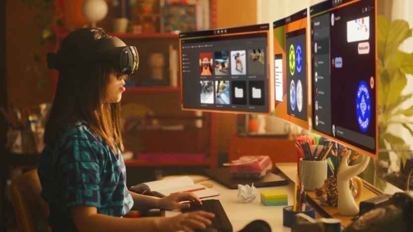 A person with long hair wearing a headset and looking at three floating virtual screens.