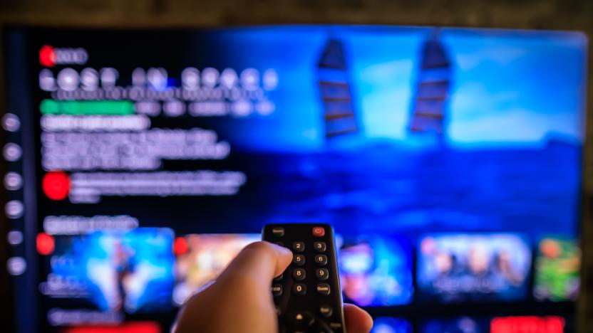 TV remote control in the foreground, Video on demand screen in the blurry background, streaming