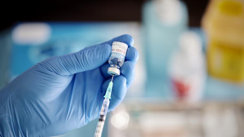 A healthcare Worker hands in surgical gloves pulling COVID-19 vaccine liquid from vial to vaccinate a patient