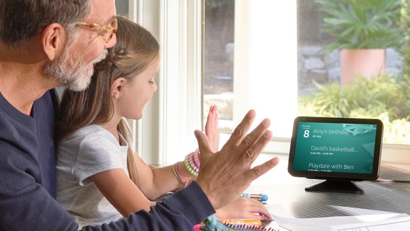 A father and daughter sitting in front of an Echo Show, holding their palms in the air to dismiss a timer.