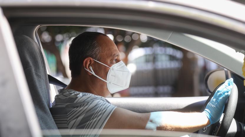 LOS ANGELES, CALIFORNIA - APRIL 16: A protestor wears a face mask and gloves as Uber and Lyft drivers with Rideshare Drivers United and the  Transport Workers Union of America conduct a ‘caravan protest’ outside the California Labor Commissioner’s office amidst the coronavirus pandemic on April 16, 2020 in Los Angeles, California. The drivers called for California to enforce the AB 5 law so that they may qualify for unemployment insurance as the spread of COVID-19 continues. Drivers also called for receiving back wages they say they are owed. (Photo by Mario Tama/Getty Images)