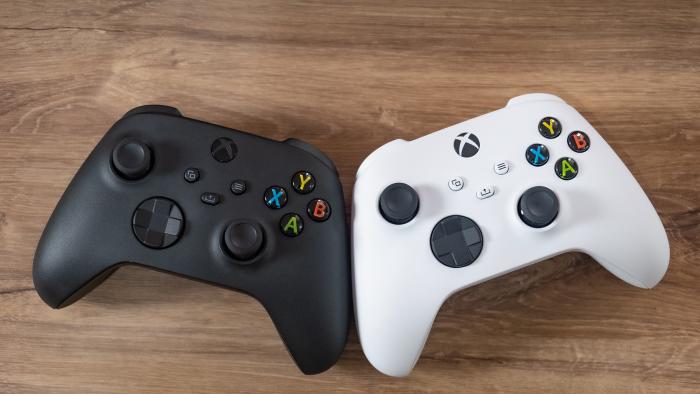 Two Xbox Wireless Controllers, one black and the other white.