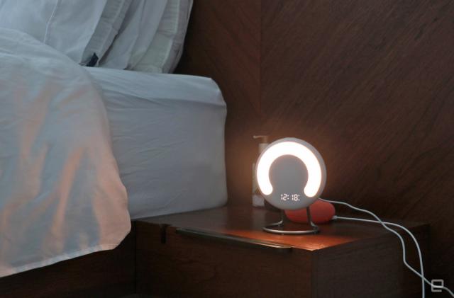 The Amazon Halo Rise on a nightstand in the dark with a the time and a semi-circle lit up on its front.