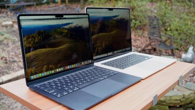 Two laptops on a table outside. 