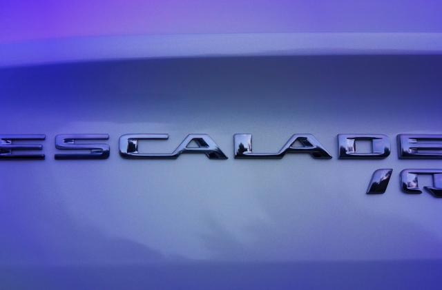 A close-up of the Cadillac ESCALADE IQ name badge seen on the vehicle. Preproduction model shown. Actual production model may vary.