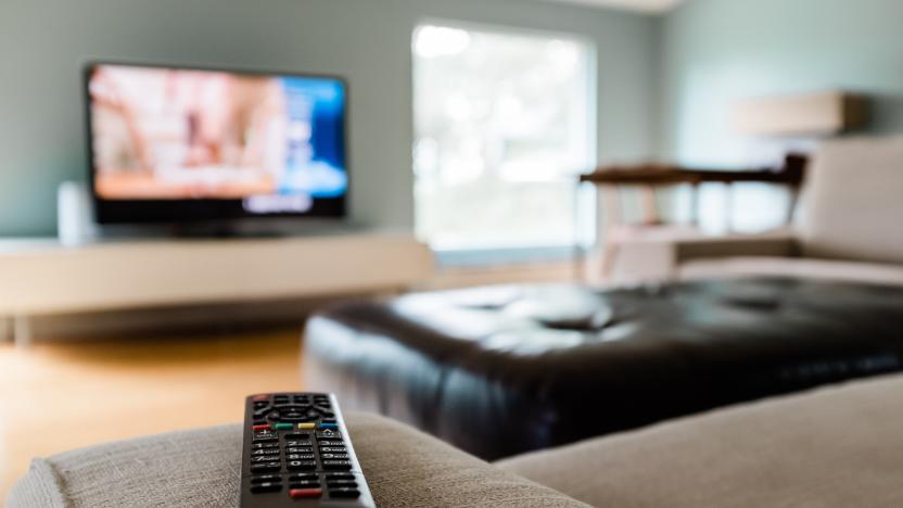 Close-up of a remote control sitting on a couch in an empty modern living room.