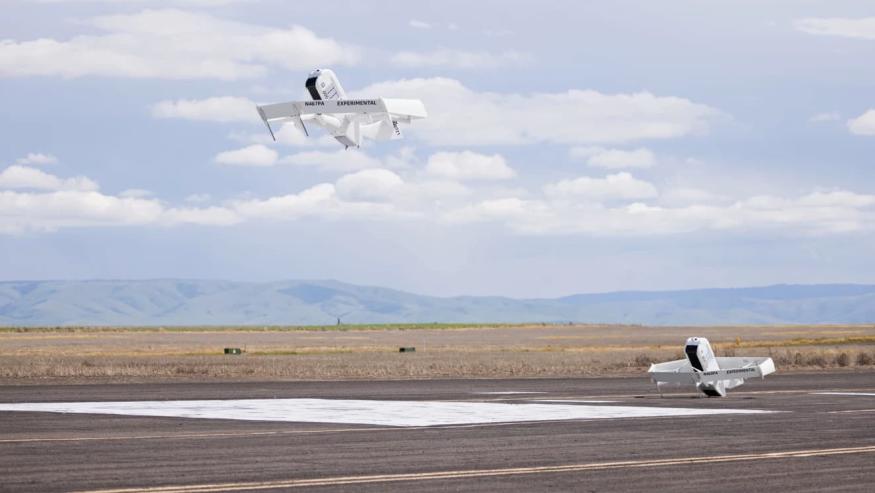 An Amazon delivery drone takes off as a second one remains on the tarmac.