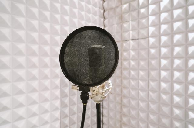 microphone with pop filter on mic stand in soundproof isolation booth for vocal recording at sound studio