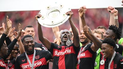 Getty Images - LEVERKUSEN, GERMANY - MAY 18: Odilon Kossounou of Bayer Leverkusen lifts the Meisterschale of Bundesliga trophy after their team's victory during the Bundesliga match between Bayer 04 Leverkusen and FC Augsburg at BayArena on May 18, 2024 in Leverkusen, Germany. (Photo by Stuart Franklin/Getty Images)