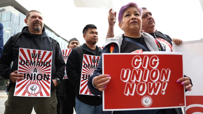 SAN FRANCISCO, CALIFORNIA - OCTOBER 12: Delivery drivers and gig workers hold signs as they protest in front of Uber headquarters on October 12, 2022 in San Francisco, California. Dozens of gig workers and delivery drivers staged a protest outside of Uber headquarters to announce the formation of the California Gig Workers Union after they say working conditions haven't improved since California voters passed Proposition 22 to classify  gig workers as independent contractors. Proposition 22 was later found to be unconstitutional under the California state constitution in August 2021 by a Superior Court judge. (Photo by Justin Sullivan/Getty Images)