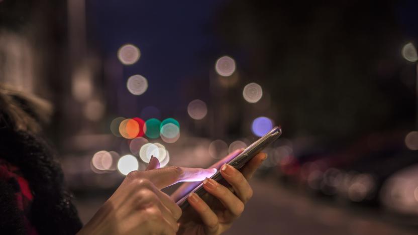 Woman using her mobile phone, city skyline night light background