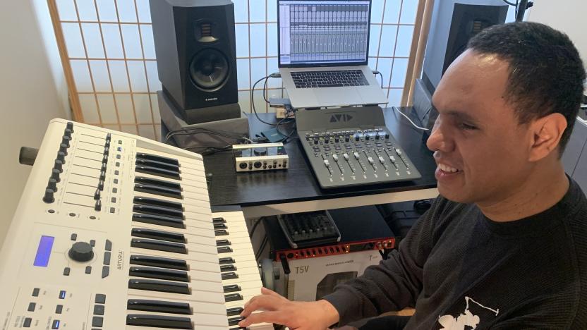 Visually impaired audio engineer Jason Dasent sits in a studio, with his right hand on a keyboard in front of him. 