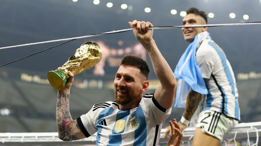 Soccer Football - FIFA World Cup Qatar 2022 - Final - Argentina v France - Lusail Stadium, Lusail, Qatar - December 18, 2022   Argentina's Lionel Messi celebrates winning the World Cup with the trophy as Argentina's Lautaro Martinez is sat on a goal frame REUTERS/Hannah Mckay