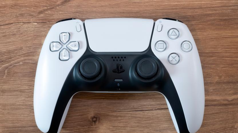 Closeup photo of a PS5 DualSense controller (white) sitting on a brown wooden surface.