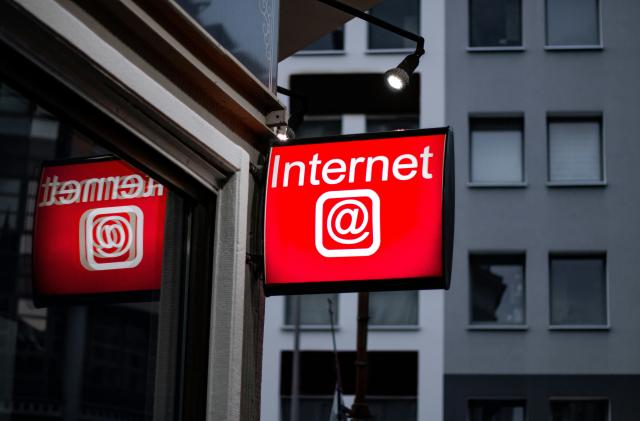 A red sign hanging outside a building. It reads "Internet" and includes an "at" symbol.