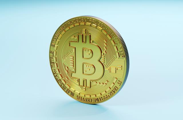 Three dimensional render of Bitcoin standing against blue background