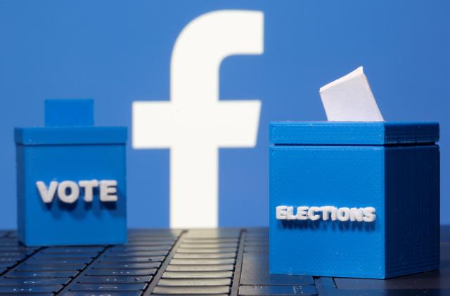 3D printed ballot boxes are seen in front of a displayed Facebook logo in this illustration taken November 4, 2020. REUTERS/Dado Ruvic/Illustration