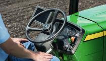 A John Deere tractor steering wheel pictured with a smart display next to it