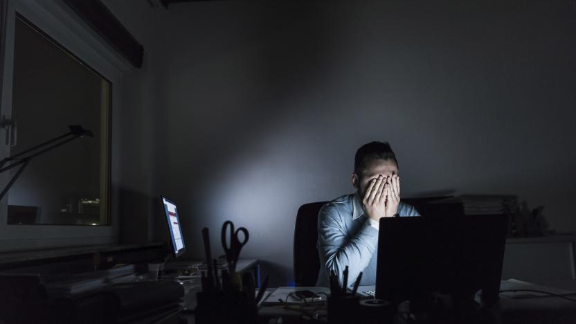 Exhausted businessman sitting at desk in office at night