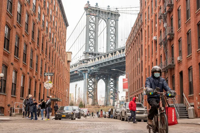 NEW YORK, NEW YORK - DECEMBER 22: A GrubHub delivery person rides a bicycle by Manhattan Bridge on December 22, 2020 in the Brooklyn borough of New York City. The pandemic continues to burden restaurants and bars as businesses struggle to thrive with evolving government restrictions and social distancing plans which impact keeping businesses open yet challenge profitability. (Photo by Noam Galai/Getty Images)