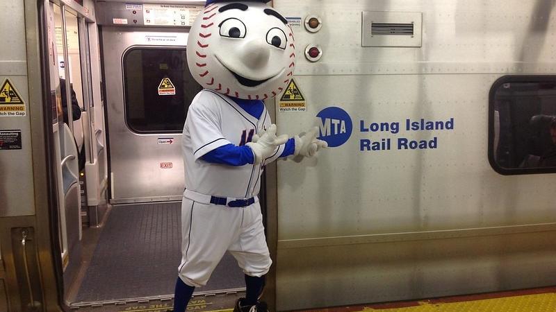 Mr. Met, the New York Mets mascot, stands in front of an MTA subway train.